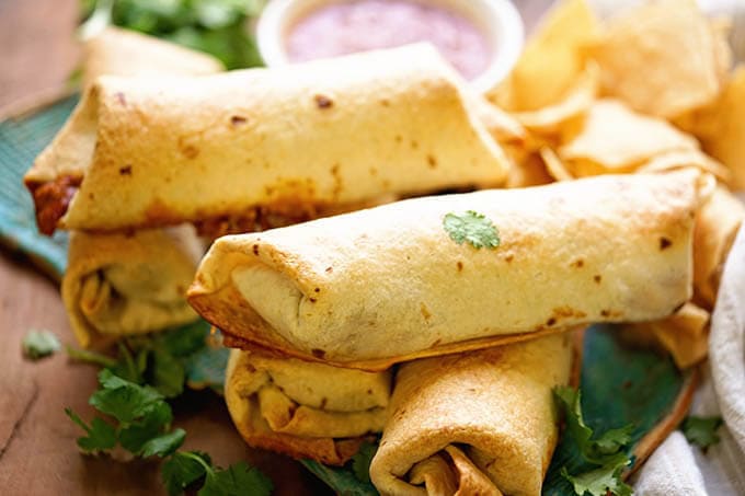 A platter of crispy chimichangas piled on a platter.