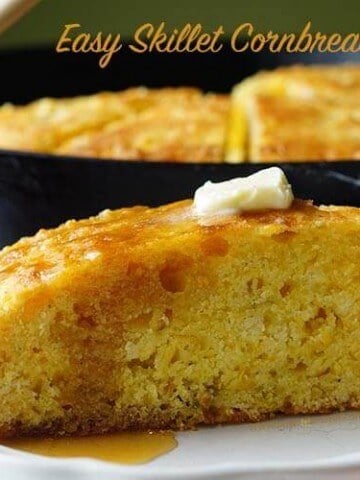 Cast Iron Skillet Cornbread Recipe on a white plate topped with butter and honey.