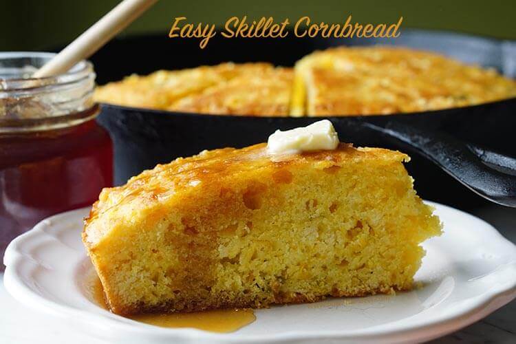 Cast Iron Skillet Cornbread Recipe on a white plate topped with butter and honey.