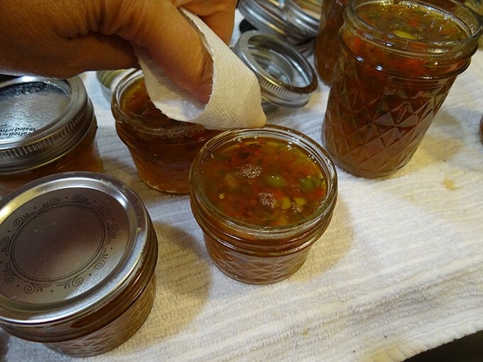 Cleaning tops of jars filled with jam. This ensures a good seal.