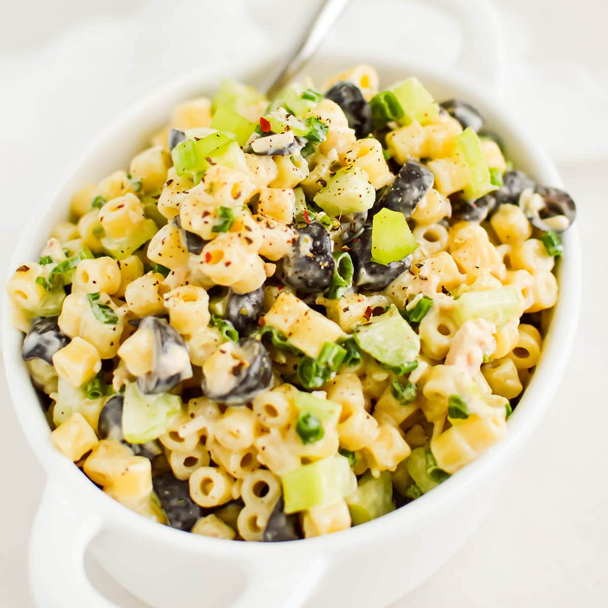 Pasta salad in bowl with serving spoon.