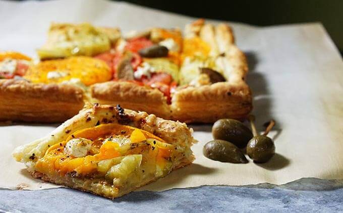 Sliced tomato tart with capers on parchment paper. 