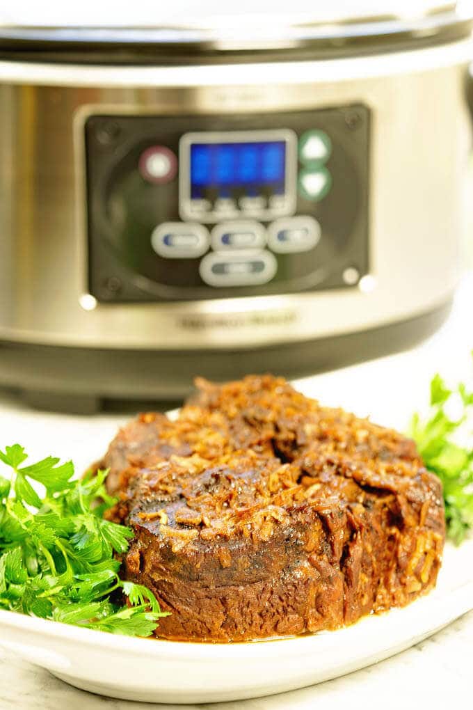 Easy Slow Cooker Roast Beef Recipe - plated on a white platter with green parsley