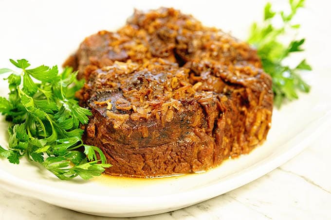 Slow Cooker Post Roast on a white platter surrounded by sprigs of parsley