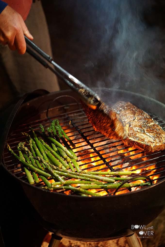 Steak on charcoal grill with asparagus.