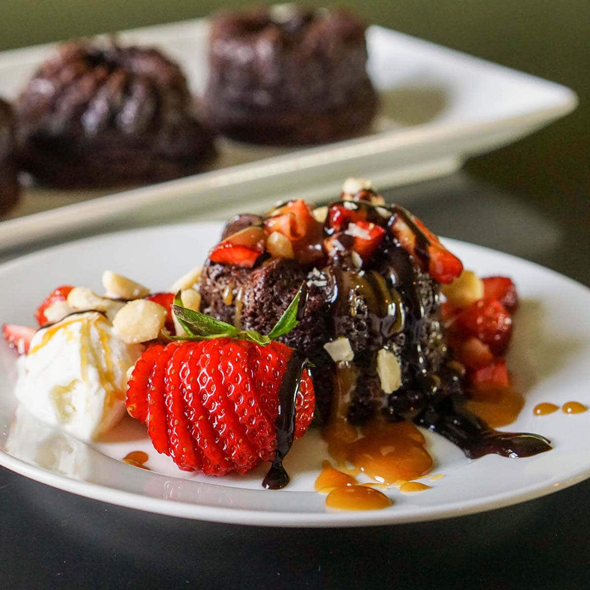 Chocolate Brownie Bundt Cake topped with ice cream, nuts and  strawberries.