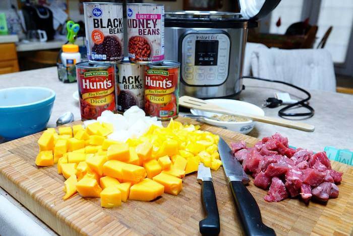 All the ingredients for butternut squash chili, diced squash and onions, stew meat and cans of beans and tomatoes with the Instant Pot.