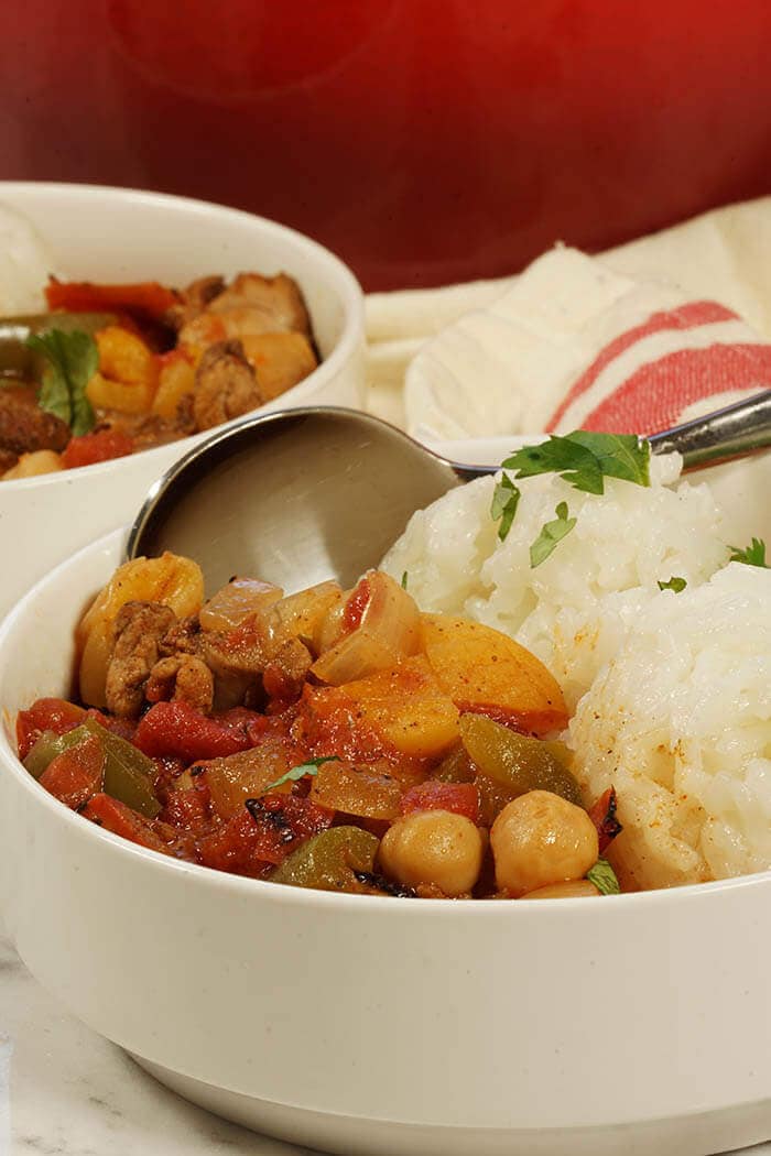 Two white bowls filled with spicy Moroccan Chicken Stew. Each meal comes with a side of white rice.