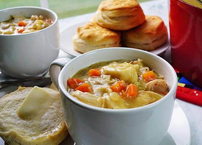 easy chicken and dumpling soup in white bowl with biscuits.