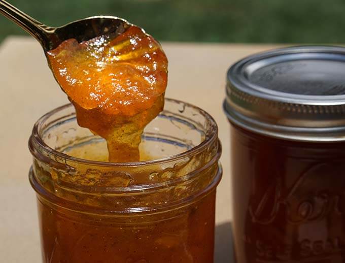 Apricot jalapeños jam in jar with spoon.