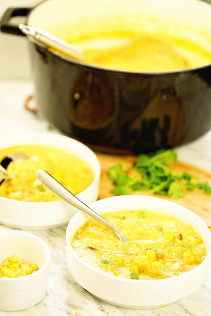 Two bowl of Vegetarian Corn Chowder with a black stock pot in the background.