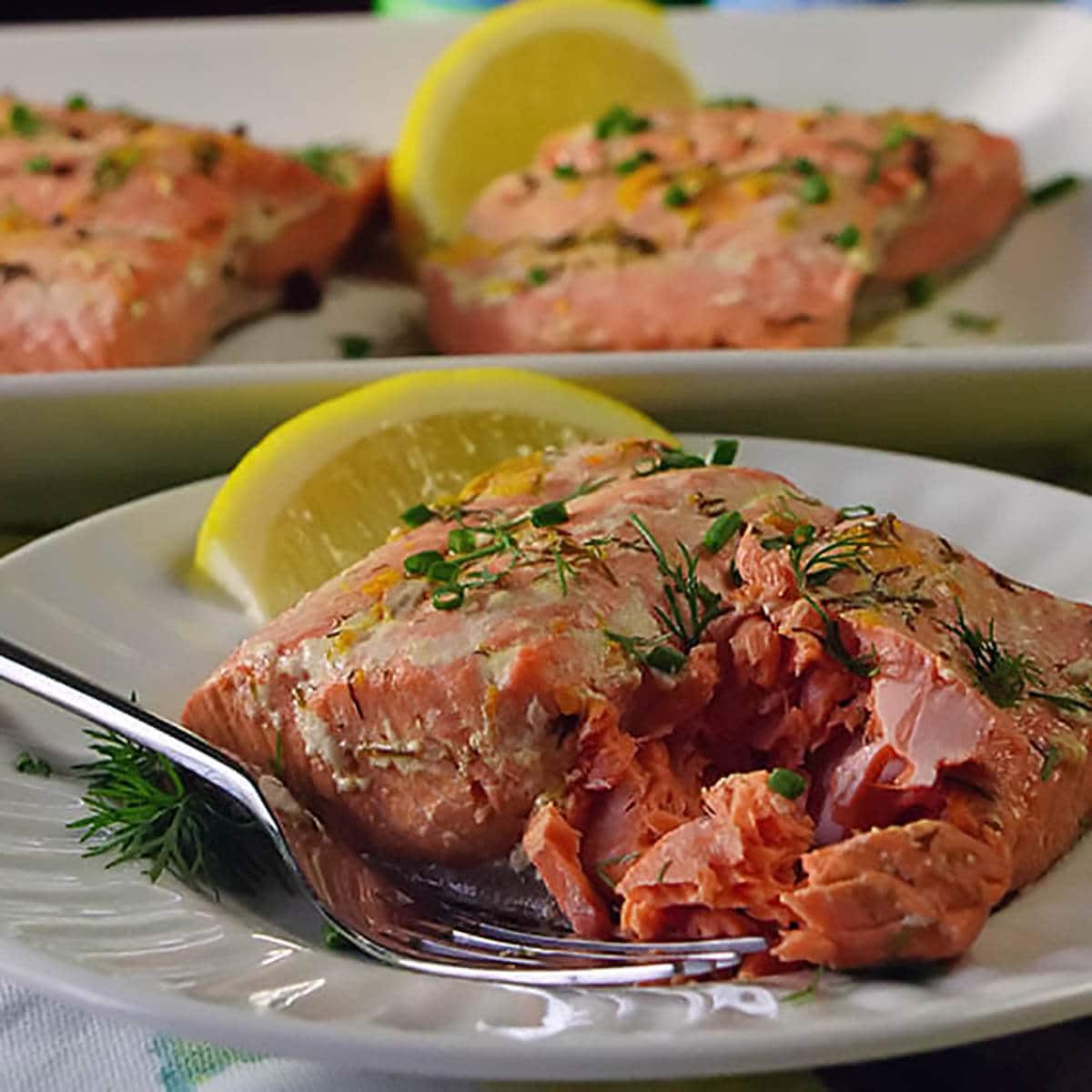 Poached salmon with lemon on a plate.