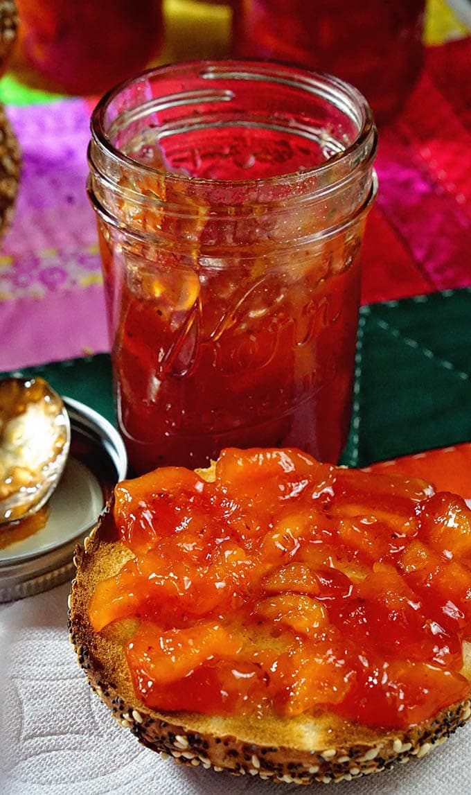 Homemade Peach Jam Recipe on an open-faced bagel surrounded by more jars, an easy peach jam recipe!