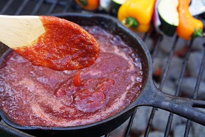 BBQ Sauce in skillet on grill with spoon.