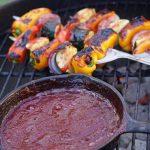 Plumb BBQ Sauce in cast iron skillet on grill with kabobs