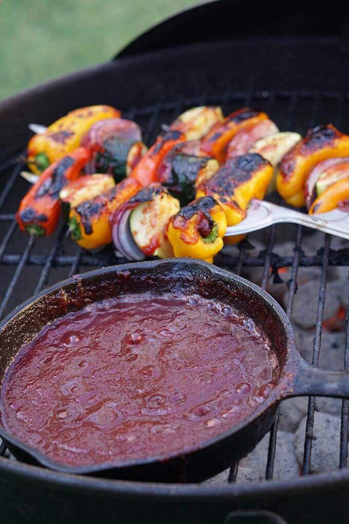 Plumb BBQ Sauce in cast iron skillet on grill with kabobs