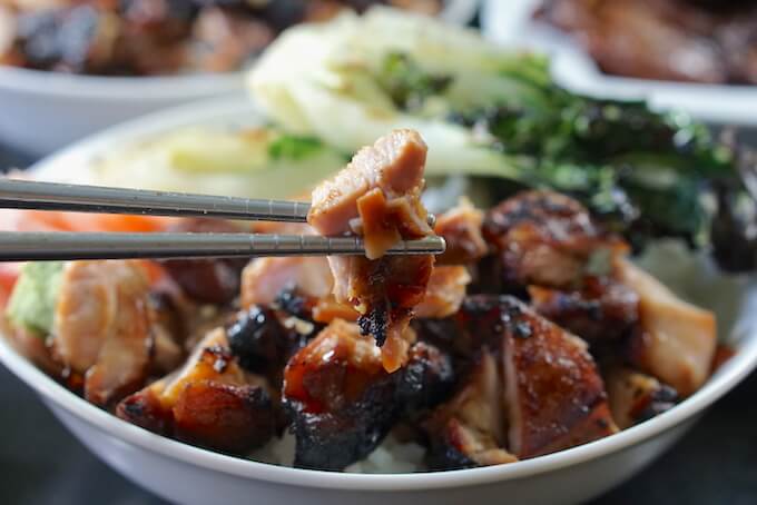 A teriyaki chicken bowl recipe. A pair of silver chopsticks have grabbed a piece of chicken. It looks tender and juicy!