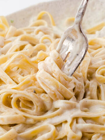 Fettuccine pasta on platter being twirled around a fork.