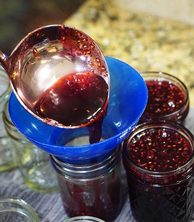 Homemade jam being ladled into jars.