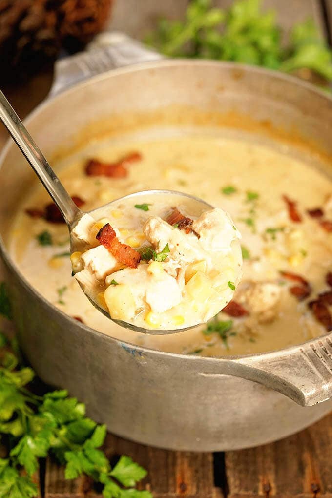 An aluminum stock pot filled with turkey chowder with corn.