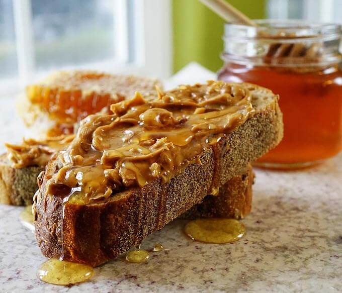 Thick slices of bread spread with chunky peanut butter topped with drizzles of honey.