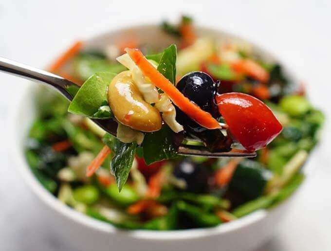 White bowl filled with kale superfood salad recipe with fork.