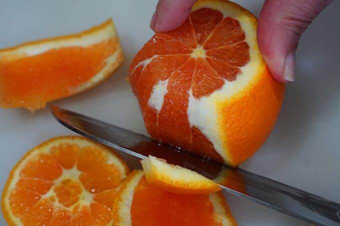 Here's how to peel an orange. Slice off the top and bottom of the orange. Then you'll slice off the the rind and pith. Work your way around the orange slowly.