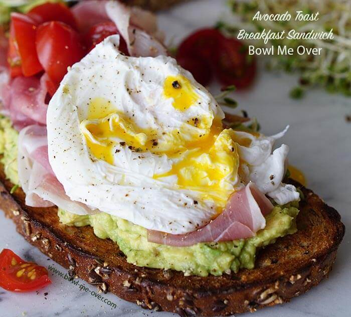 Avocado breakfast sandwich topped with poached egg. 