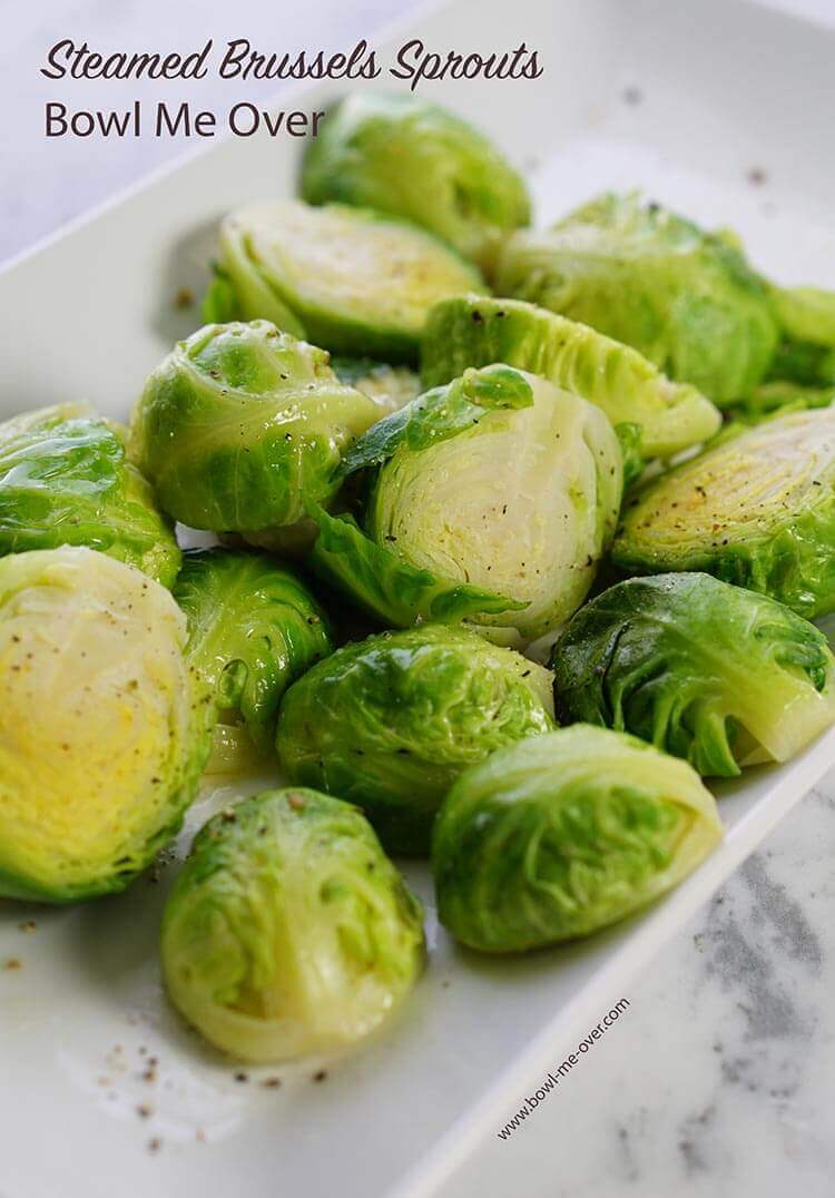 A white plate on a marble countertop. The plate is full of steamed fresh Brussels sprouts!