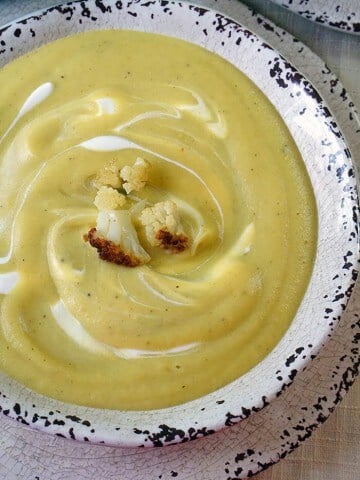 A white bowl filled with creamy cauliflower soup.