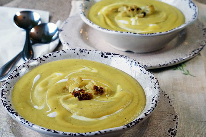 Two bowl of Roasted Cauliflower Soup Recipe in white bowls with spoon.