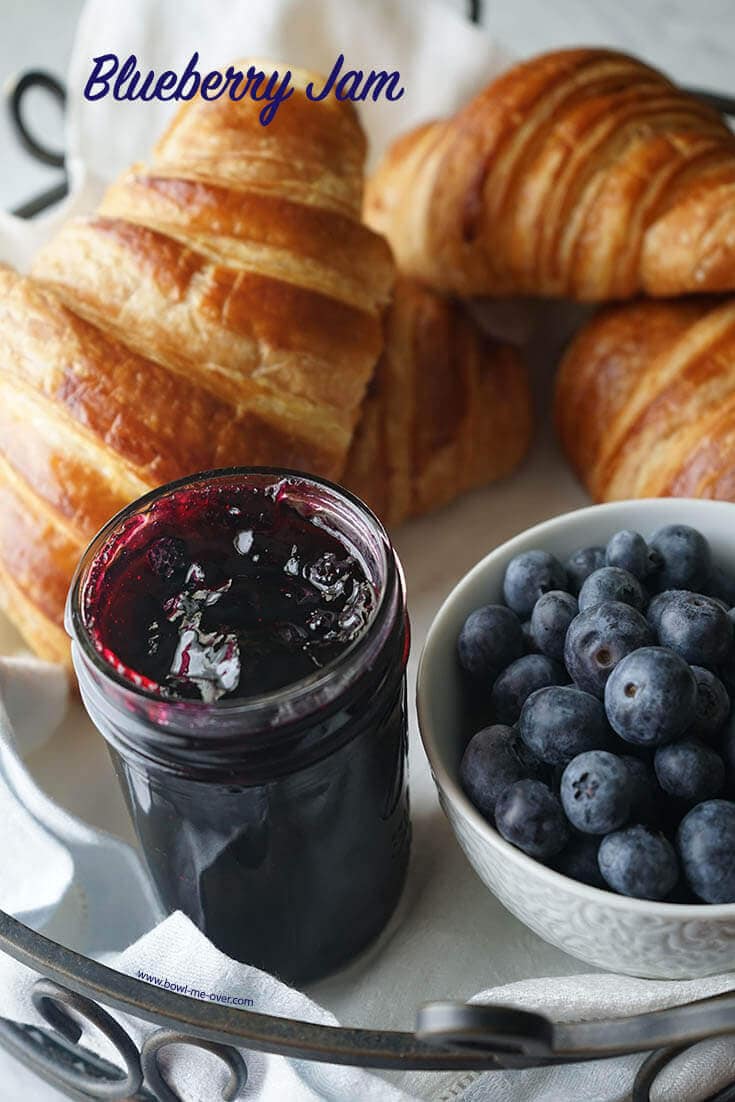 Jar of blueberry jam with fresh blueberries on the side. 