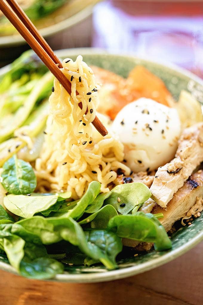 Ramen noodle bowl with soft boiled egg, chicken and vegetables with chopsticks.