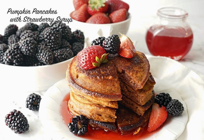 Stack of flapjacks drizzled with syrup and topped with fresh fruit.