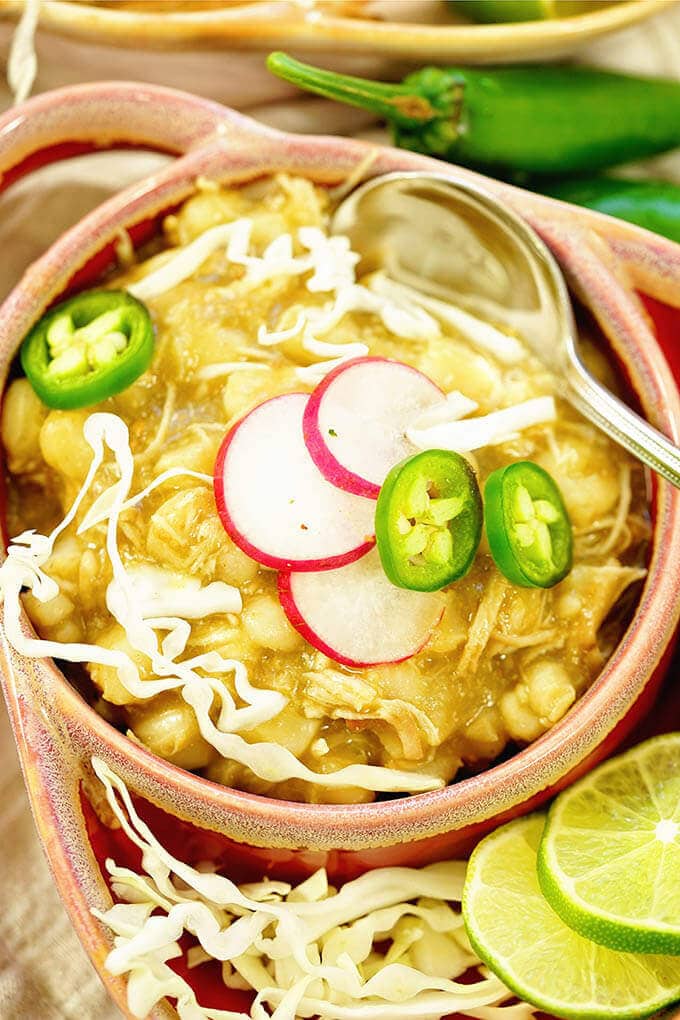 Chicken Pozole in a bowl topped with jalapeños, radishes and cabbage.