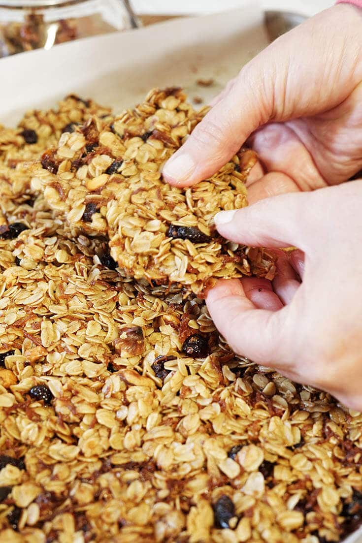 Baked granola being broken into chunks. 