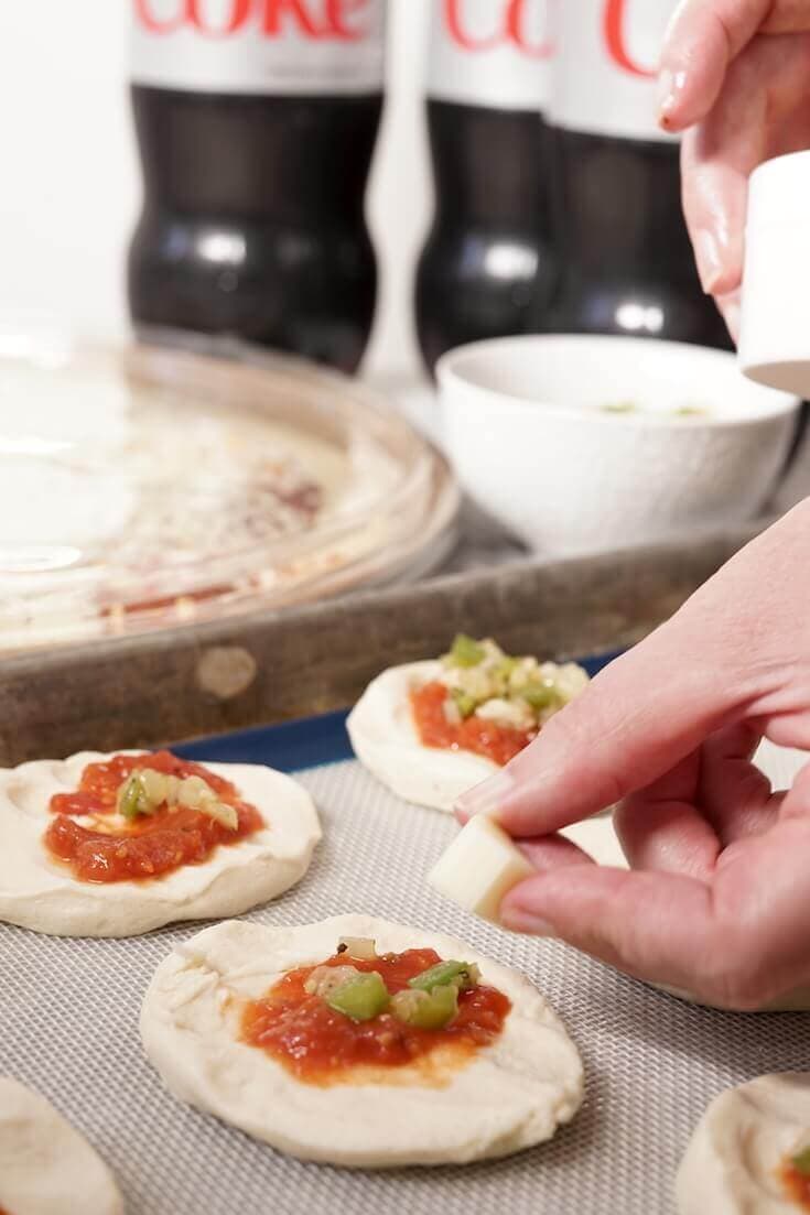 Hand placing a small chunk of cheese in the middle of the pizza bomb.