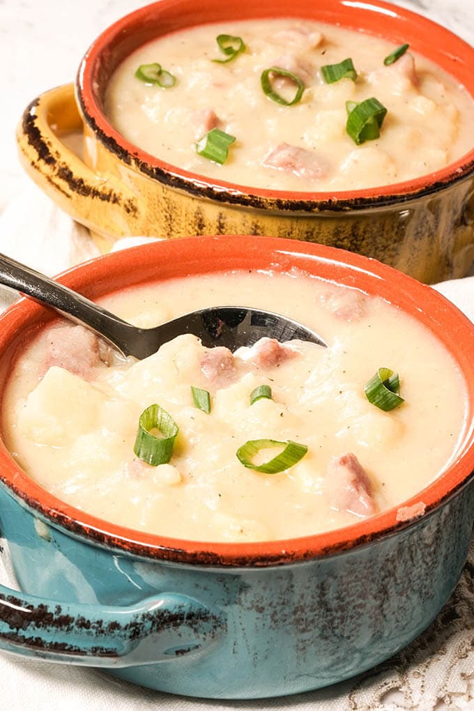 Bowls filled with Ham and Potato Soup with spoon.