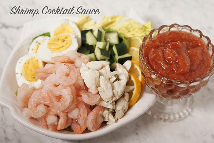 A plate of seafood, crab, eggs and cucumbers with red cocktail sauce. 