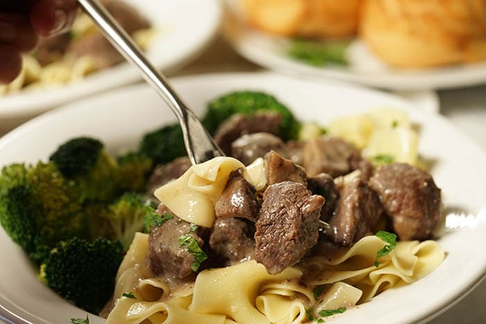 Beef Tips with Gravy over noodles with broccoli.