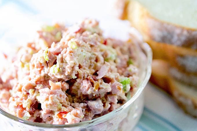 Ham Sandwich spread in a clear glass bowl with sandwiches