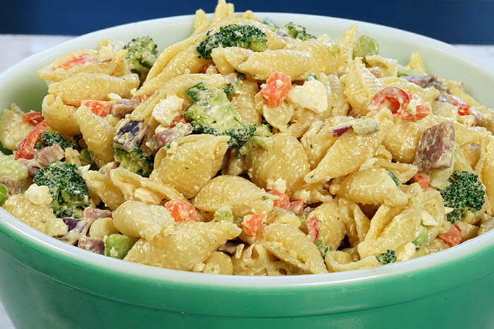 A green bowl filled with Ham and Cheese Pasta Salad. It's a big bowl piled high and there's enough for everyone!