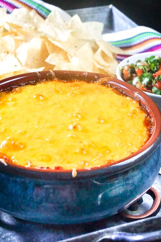 Refried Bean Dip topped with melted cheese in a blue ceramic bowl