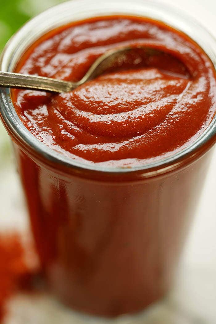 Red Chili Enchilada sauce in jar with spoon.