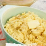 A green bowl filled with mashed potatoes made in the pressure cooker. A serving dish of gravy is ready to be poured over top.
