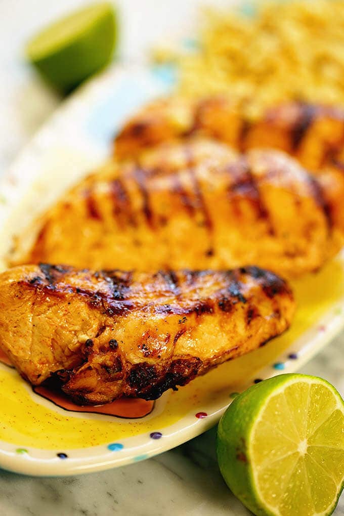 A platter of grilled Chili Lime Chicken Recipe with a wedge of lime to squeeze over top.