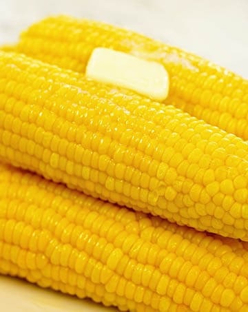 A white platter filled with corn cooked in a pressure cooker.