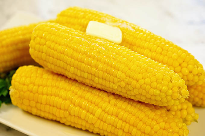 A white platter filled with corn cooked in a pressure cooker.