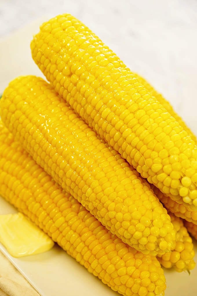 A pile of fresh sweet corn topped with butter. Instant Pot Corn on the Cob 