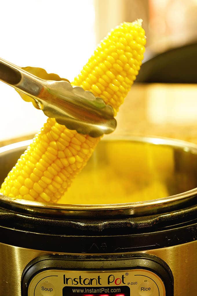 An ear of corn being placed into the Instant Pot for Instant Pot Corn on the Cob